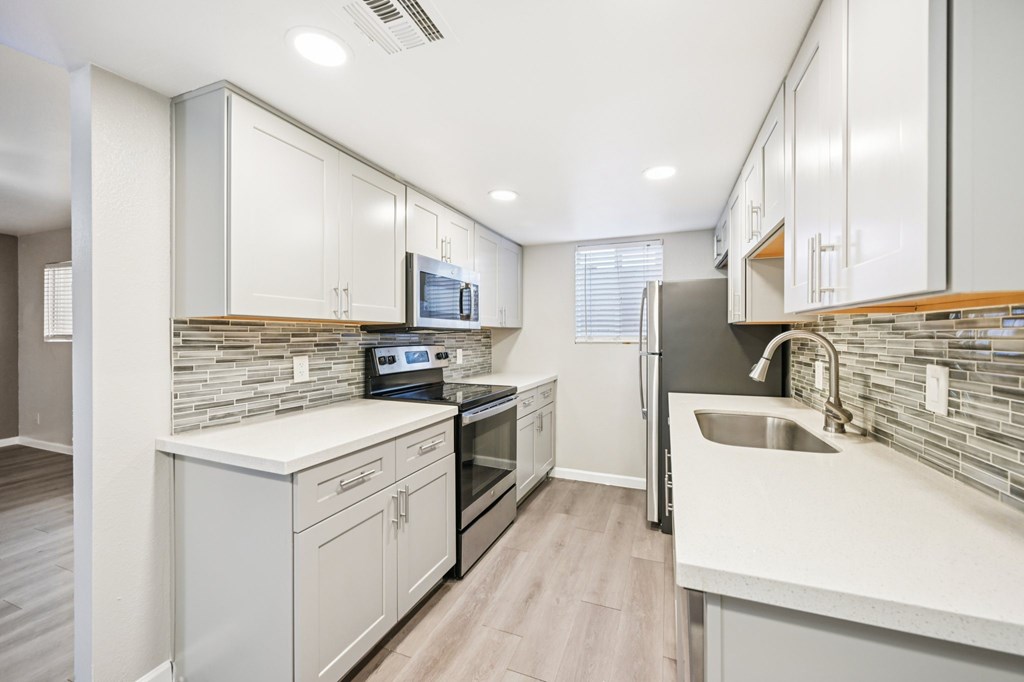 A modern kitchen with white cabinets and a stone backsplash.