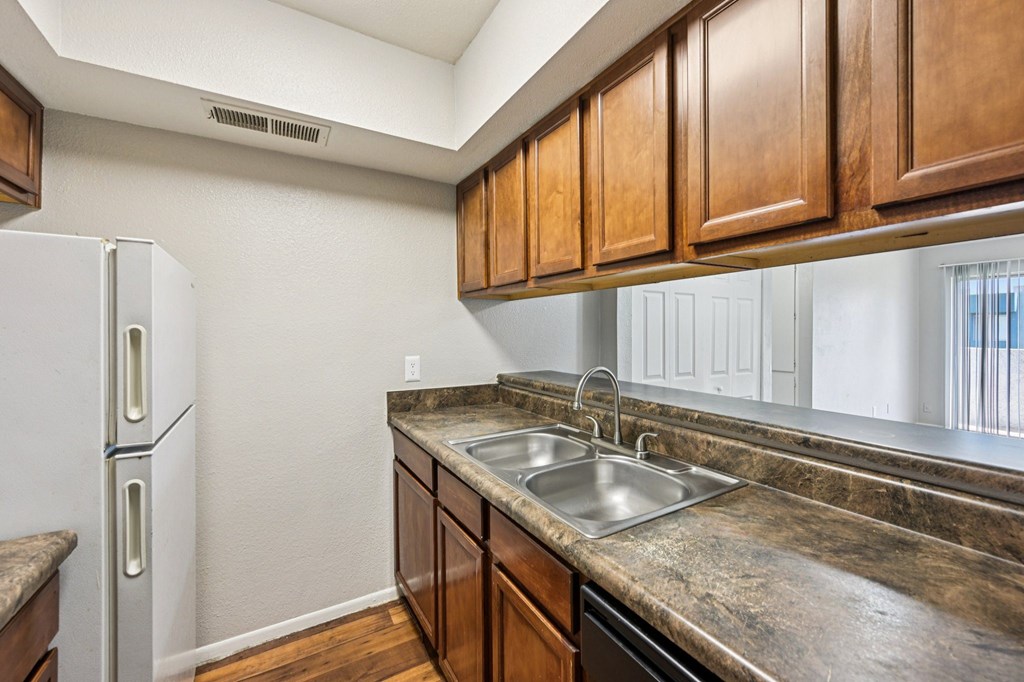 A kitchen with a white refrigerator and brown cabinets.