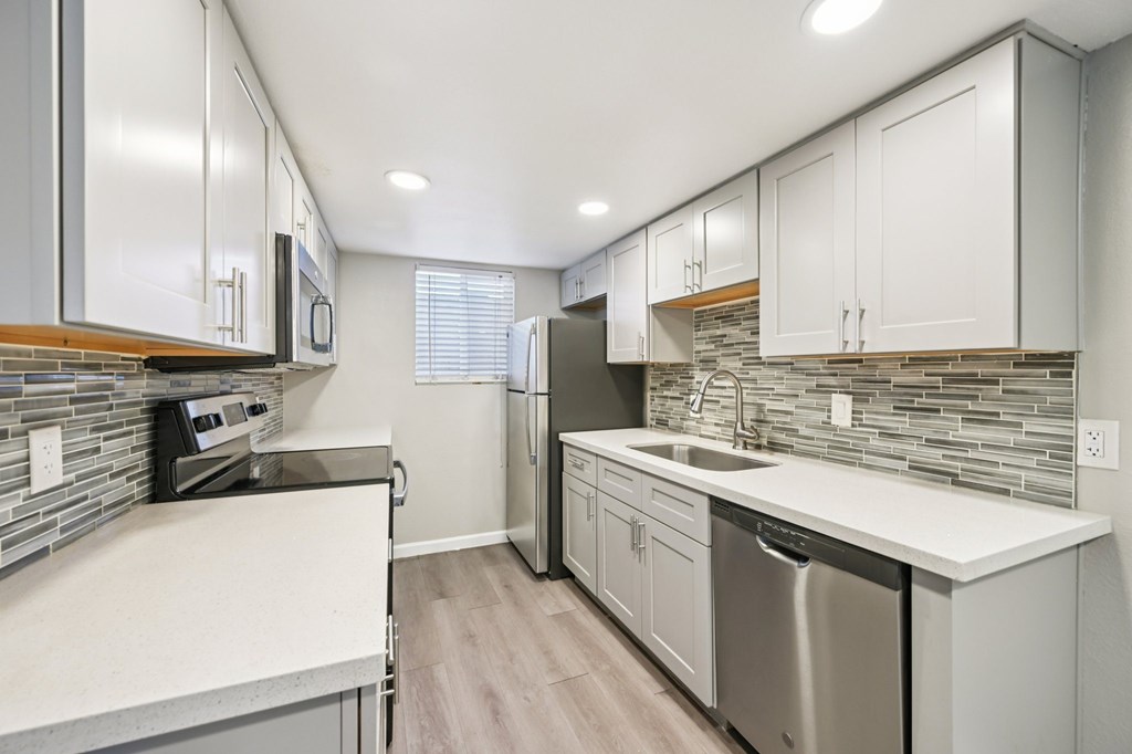 A kitchen with white cabinets and a stainless steel dishwasher.