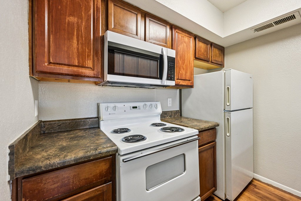 A kitchen with a white stove and a white refrigerator.