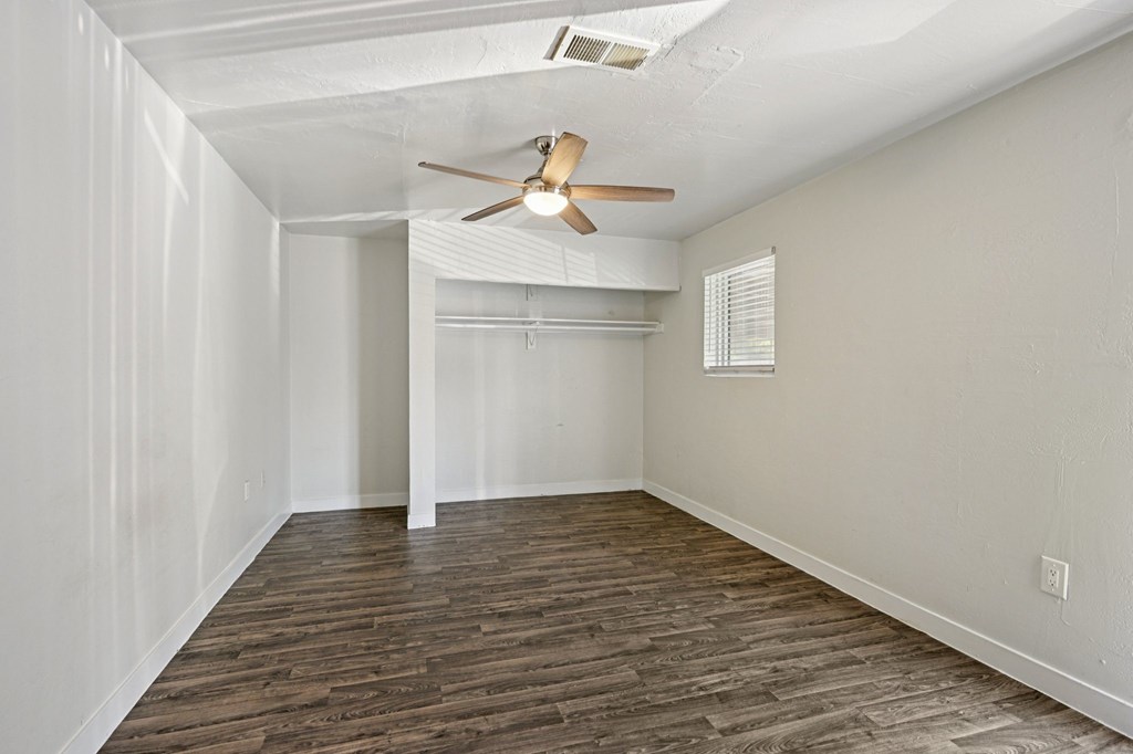 A room with a ceiling fan and wooden flooring.