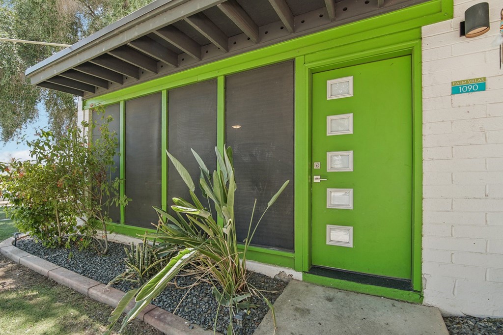 A green door with a white frame and a sign on it.