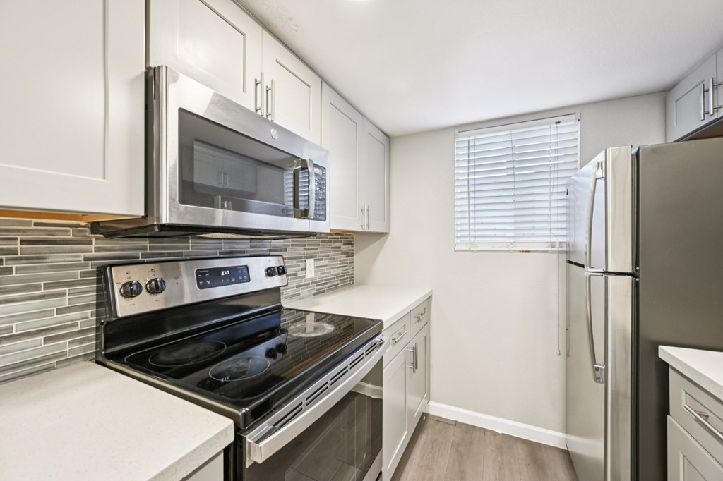 A kitchen with a stove, microwave, and refrigerator.