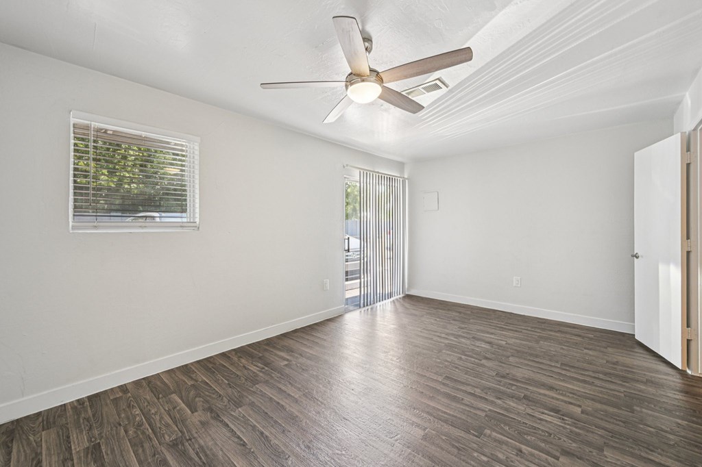 A room with a ceiling fan and wooden flooring.