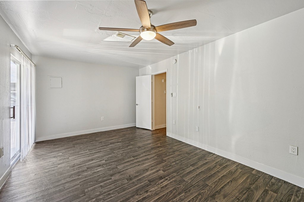 A room with a ceiling fan and wooden flooring.