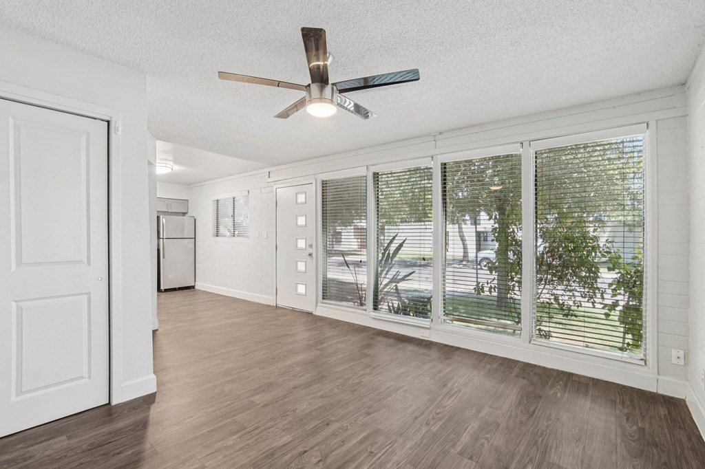 A room with a ceiling fan and sliding glass doors.