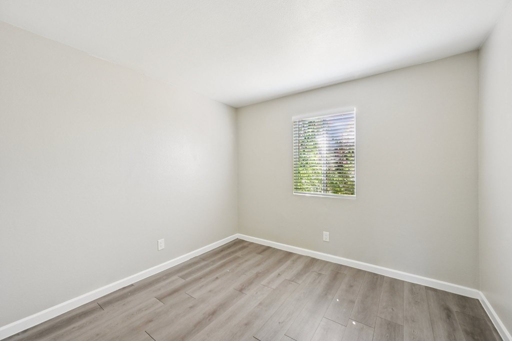 A room with a window and wooden flooring.