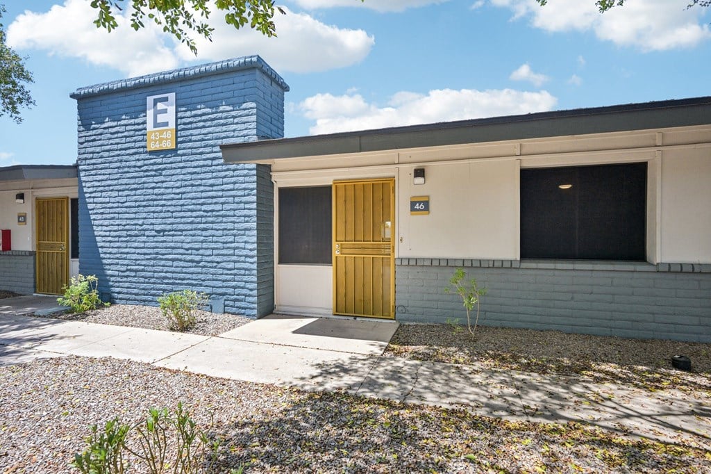A blue building with a yellow door and a sign with the letter E on it.