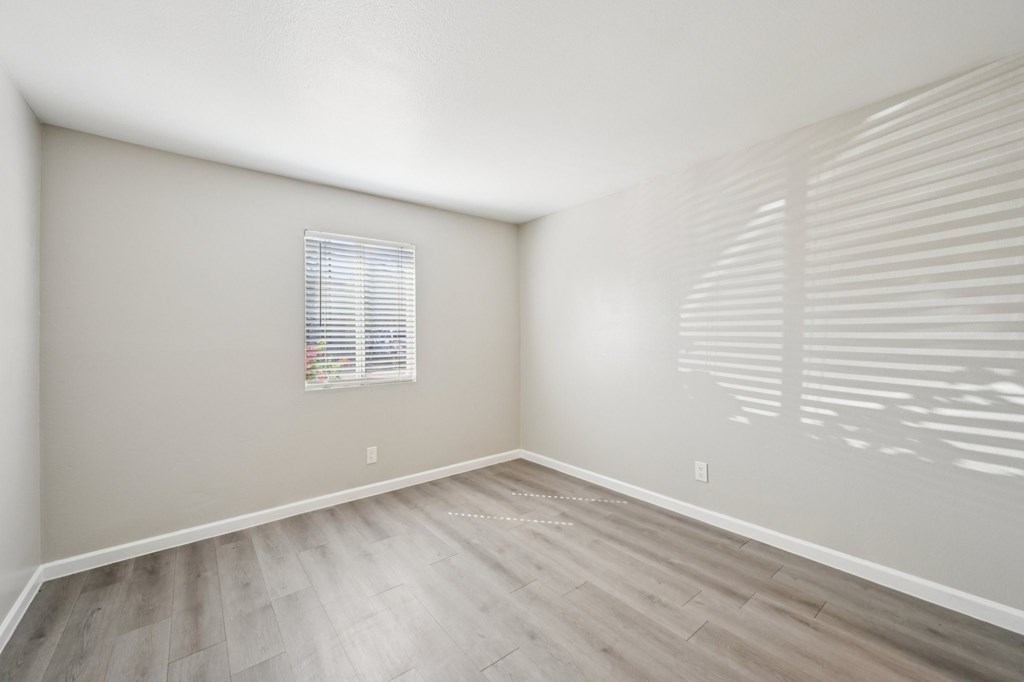 A room with a window and wooden flooring.