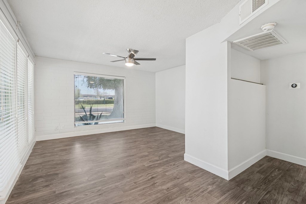 A room with a ceiling fan and a window overlooking a patio.
