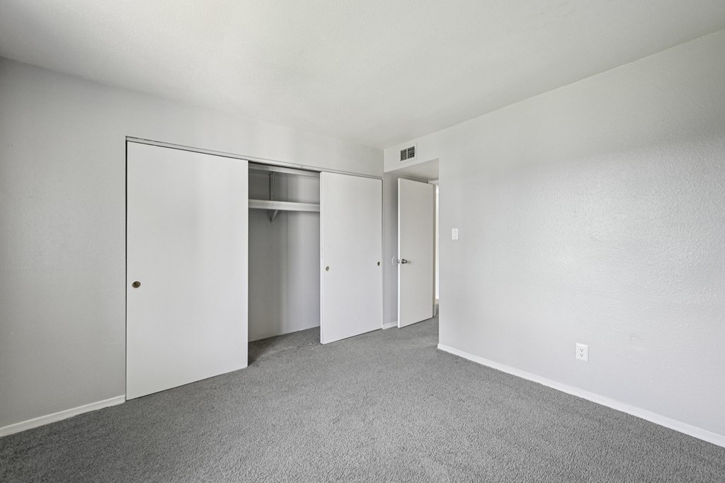 A white room with a grey carpet and three white doors.