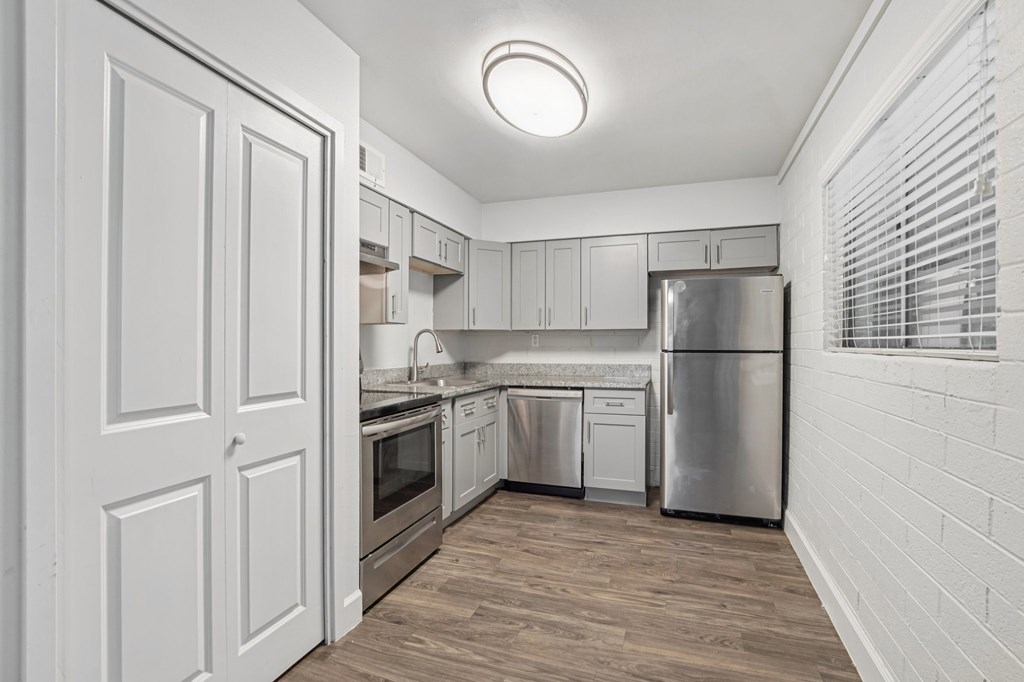 A kitchen with white cabinets and a wooden floor.