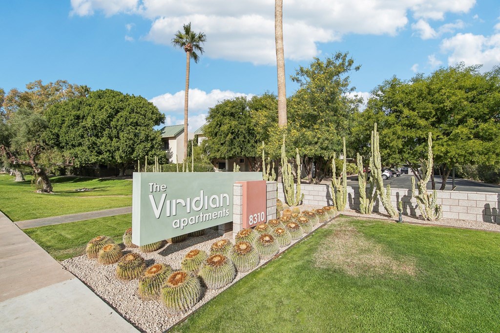 A sign for The Viridian Apartments is surrounded by cacti and trees. at The Viridian Apartments, Scottsdale