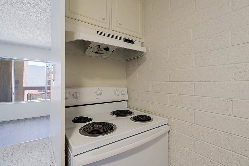 A white stove is installed in a kitchen with white walls.