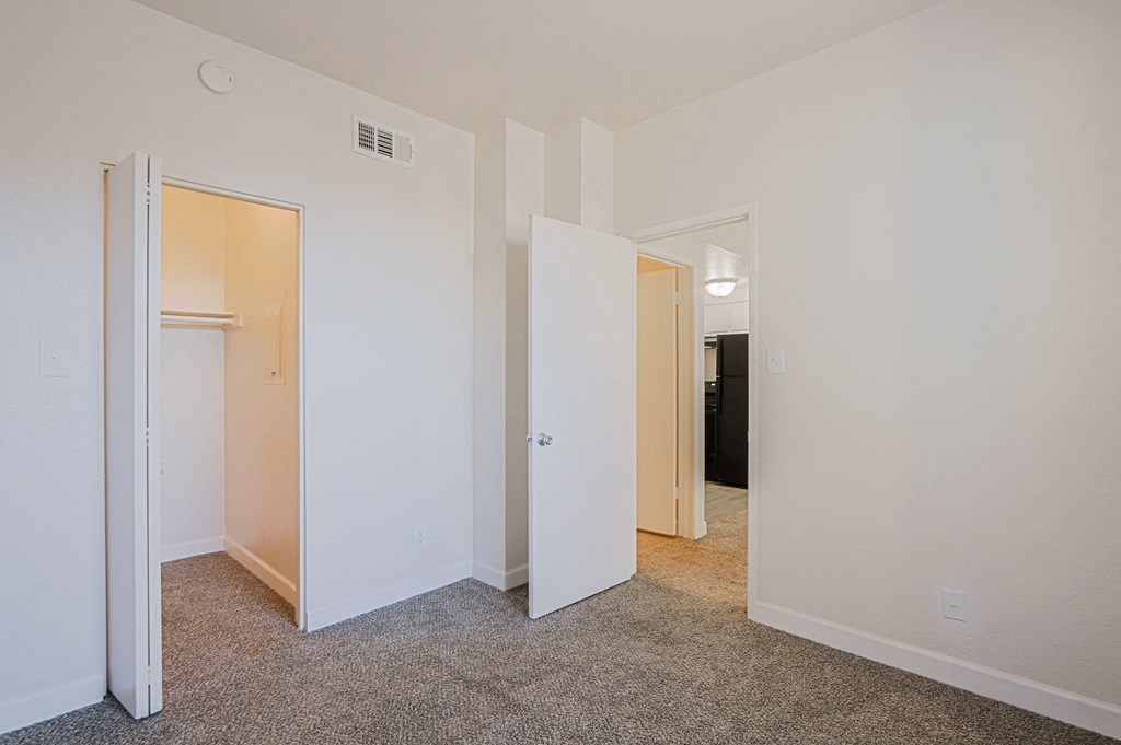 a bedroom with white walls and doors and a carpeted floor