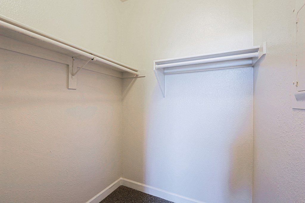 a walk in closet with a white wall and a sliding closet door