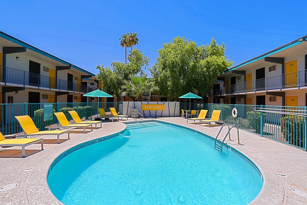 A swimming pool surrounded by yellow sun loungers and green umbrellas.