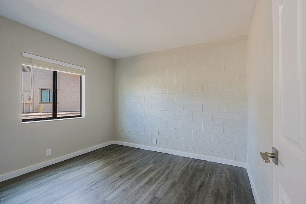 A room with a window and a wooden floor.