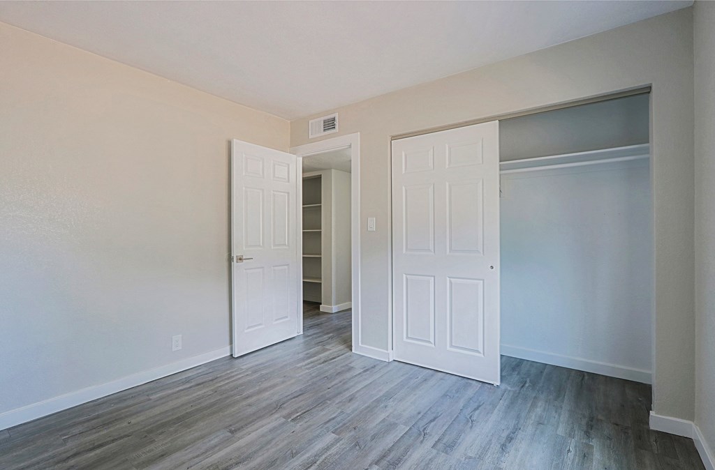 A room with white doors and grey flooring.