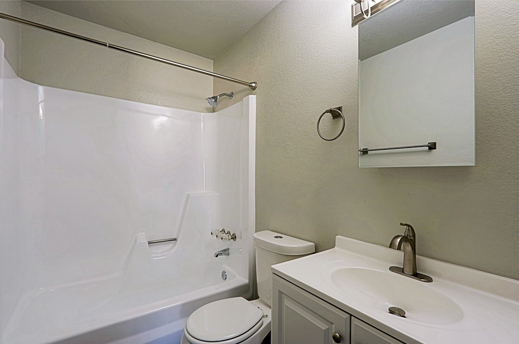 A white toilet sits next to a white bathtub in a bathroom.
