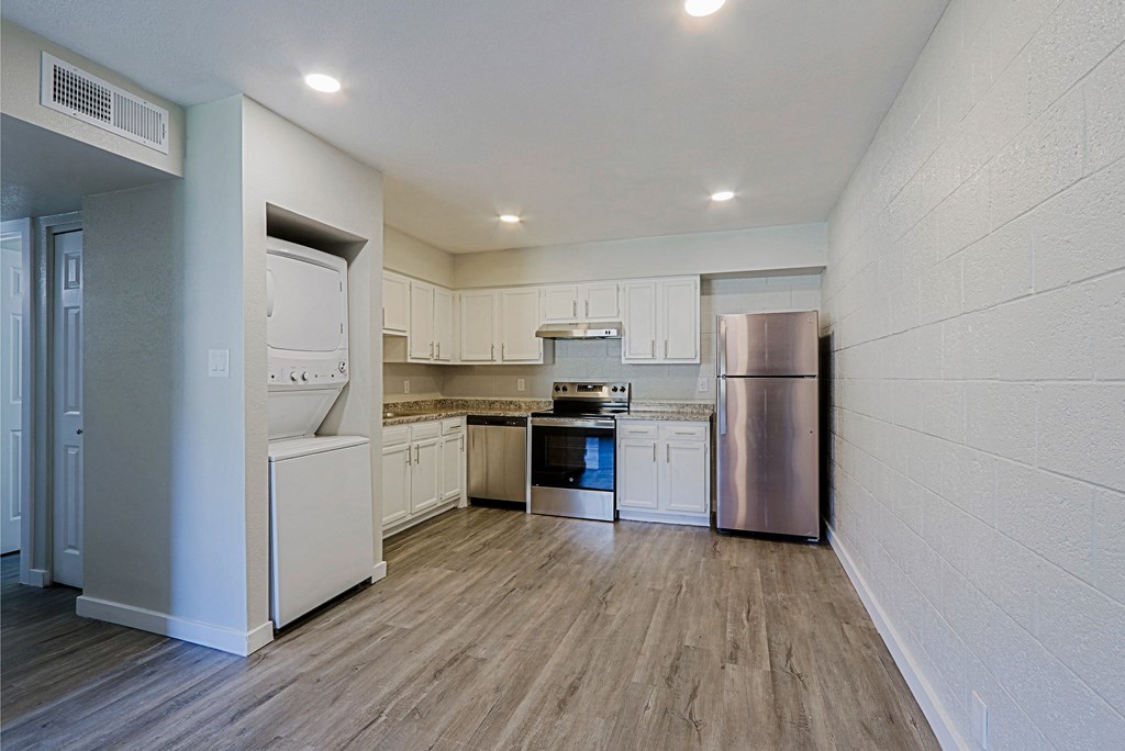 A kitchen with white appliances and wooden floors.