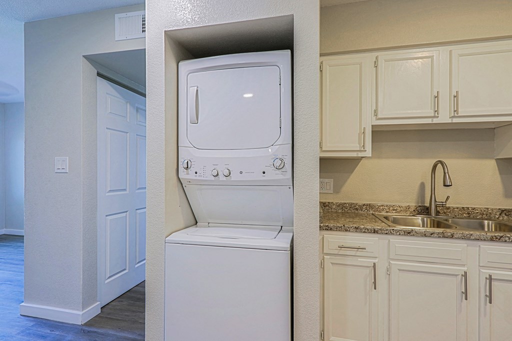 A white dishwasher is in a kitchen with white cabinets.