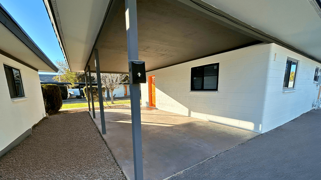 a side view of a white building with a driveway and a parking meter