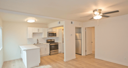 A kitchen with white appliances and wooden floors.