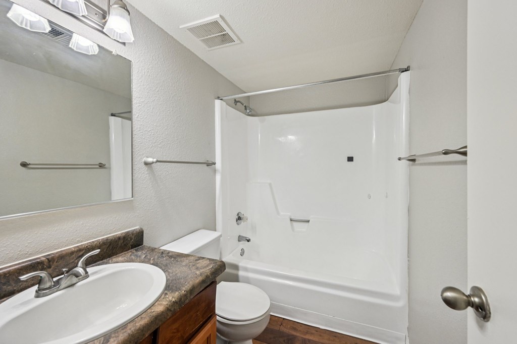 A white bathroom with a toilet, sink, and shower.