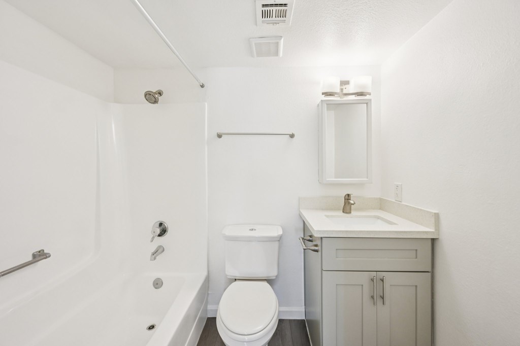 A white bathroom with a toilet, sink, and bathtub.