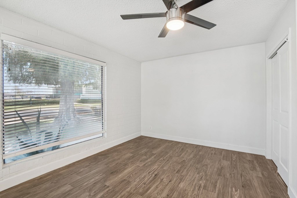 A room with a ceiling fan and a window with blinds.