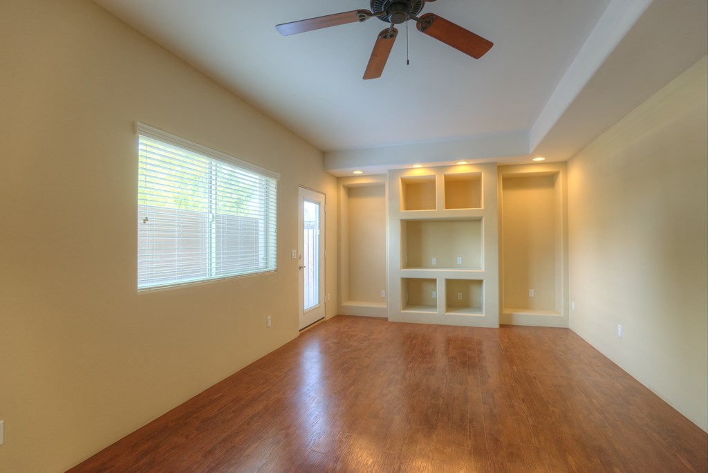 an empty living room with a ceiling fan and a window
