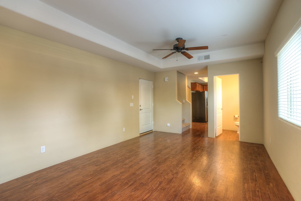 an empty living room with a ceiling fan and wood floors