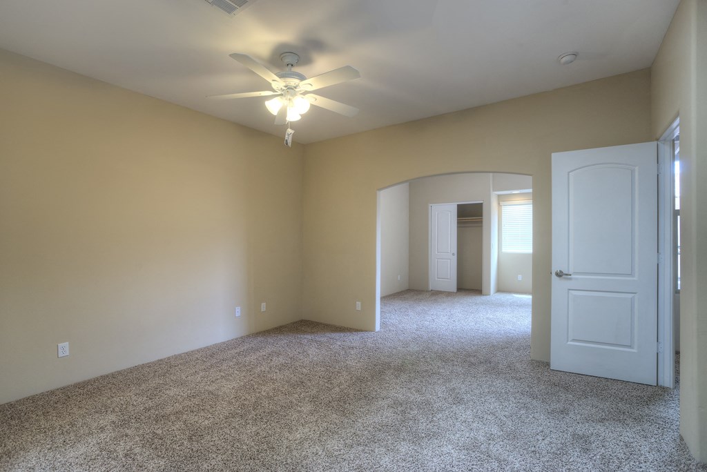 an empty living room with a ceiling fan and a white door
