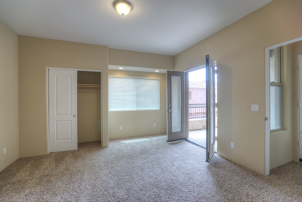 an empty living room with a door to a closet and a window