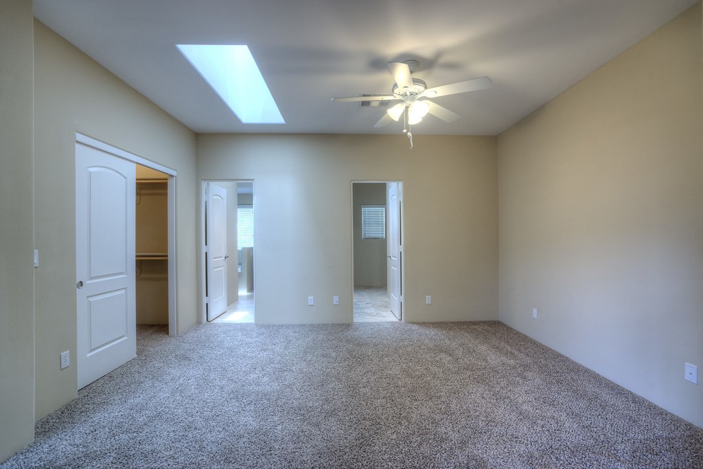 an empty living room with a ceiling fan and a closet