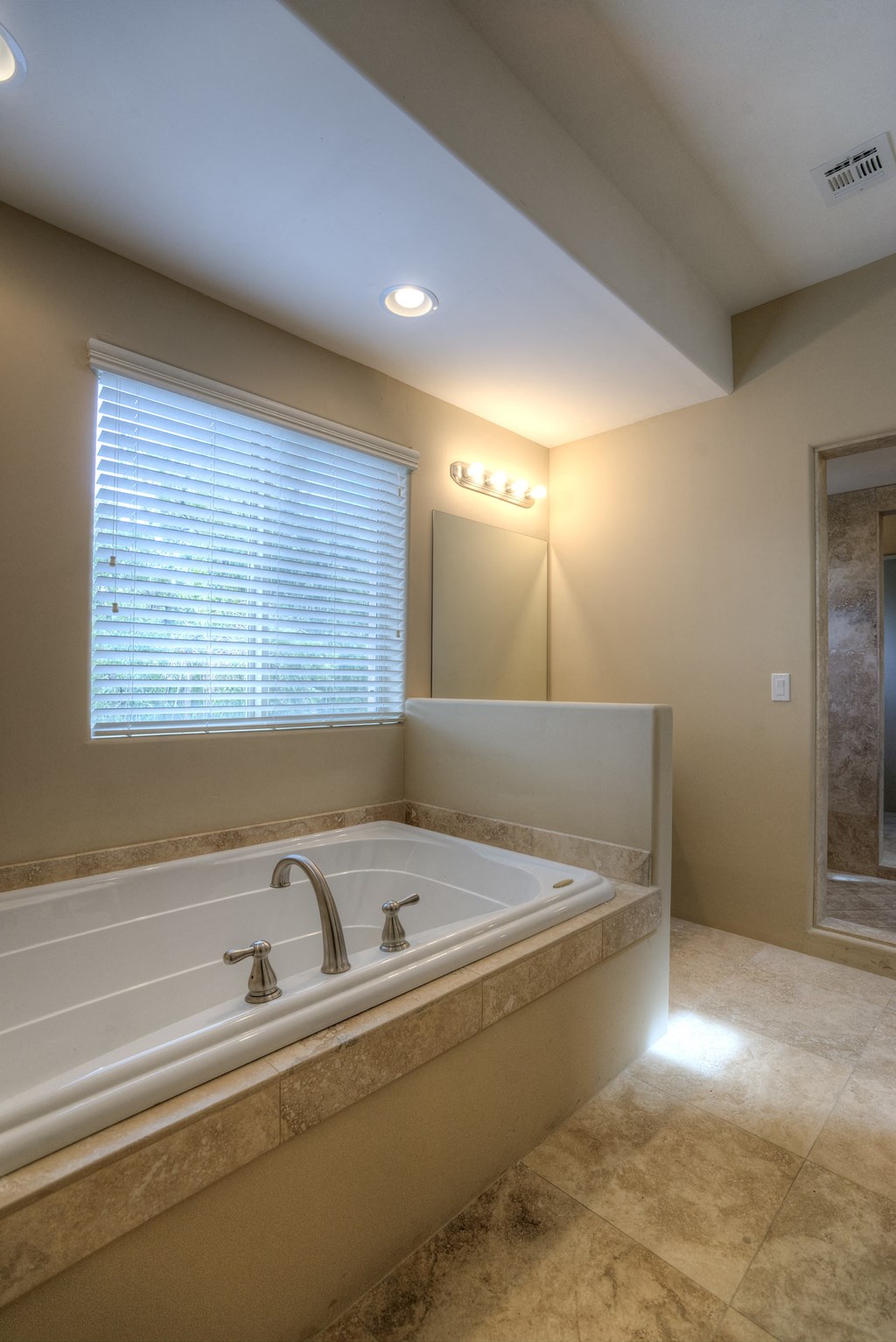 the master bathroom has a large tub and a large window