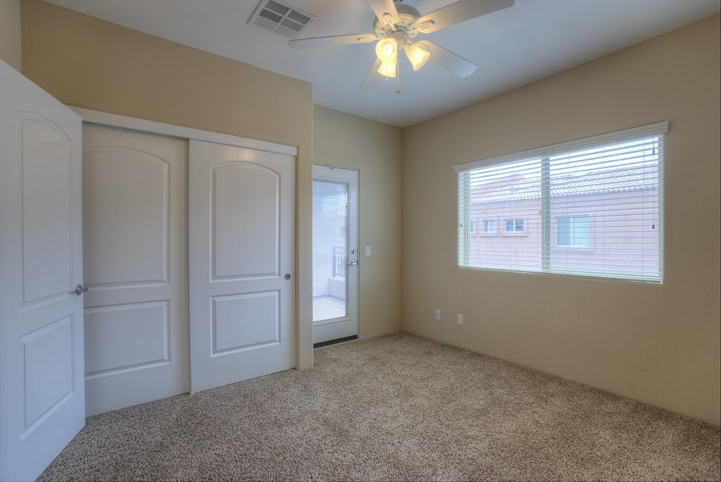 an empty bedroom with a ceiling fan and a window