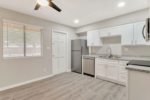 an empty kitchen with white cabinets and a stainless steel refrigerator