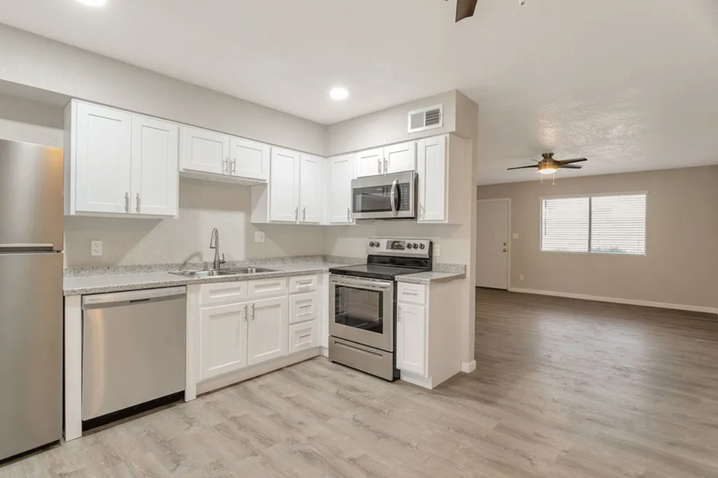an empty kitchen with white cabinets and stainless steel appliances
