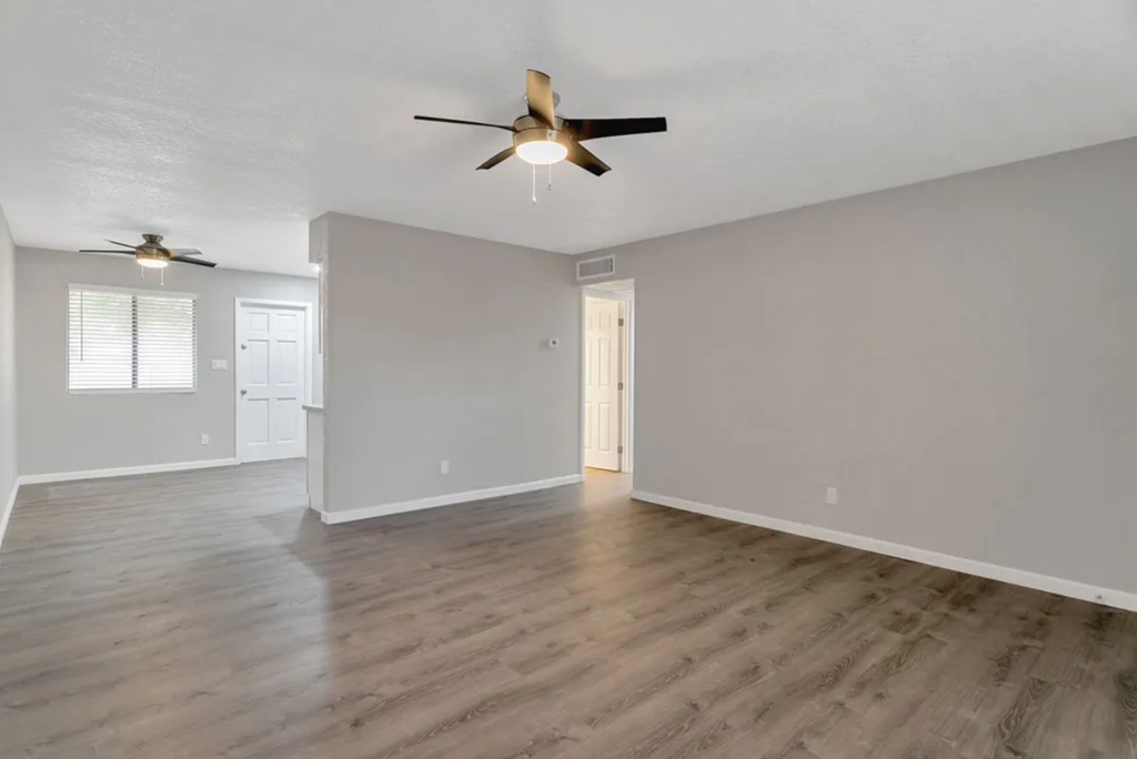the living room and dining room of an empty house with a ceiling fan