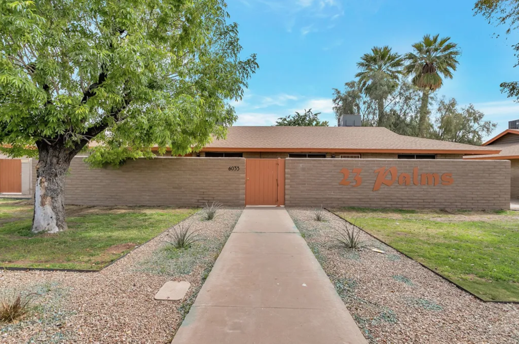 a house with a tree and a sidewalk in front of it
