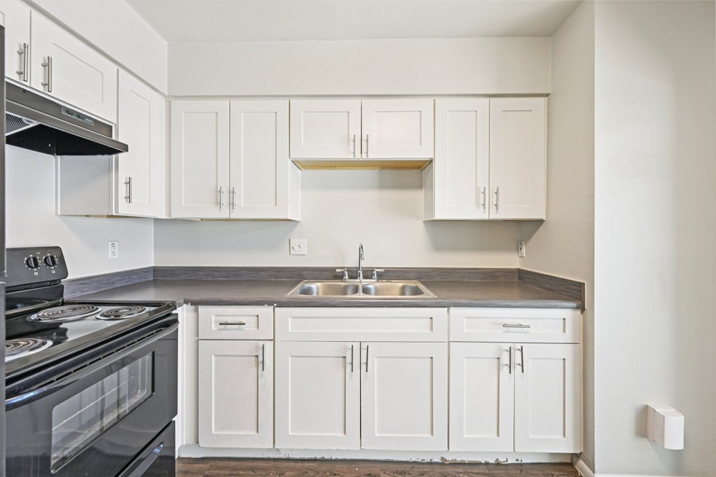 A kitchen with white cabinets and a black stove top oven.