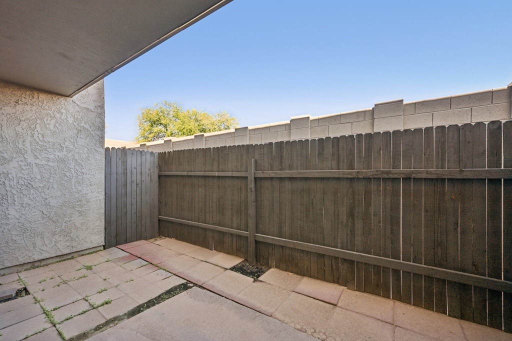 A concrete patio with a wooden fence and a wall.