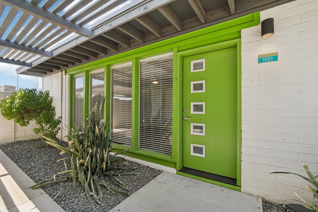 A green door is on the side of a white building.