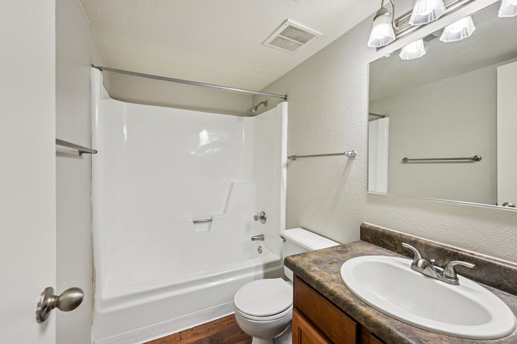 A white bathroom with a toilet, sink, and shower.