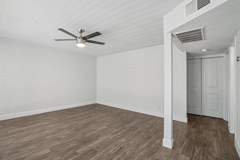 A room with a ceiling fan and wooden flooring.