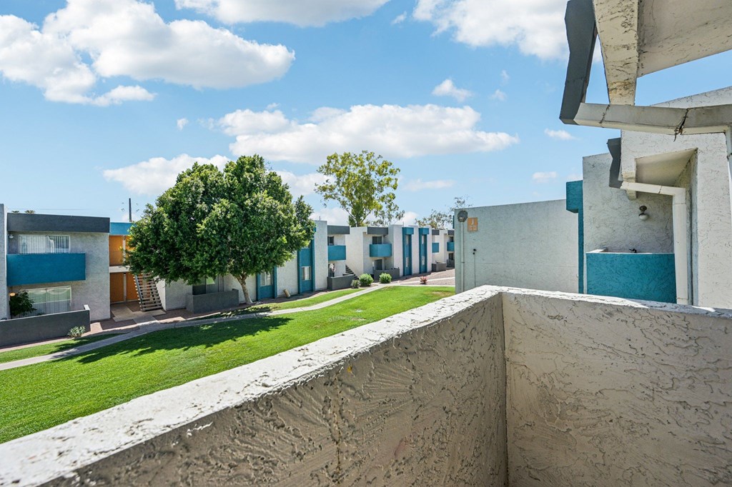 A concrete wall separates a grassy area from a building.