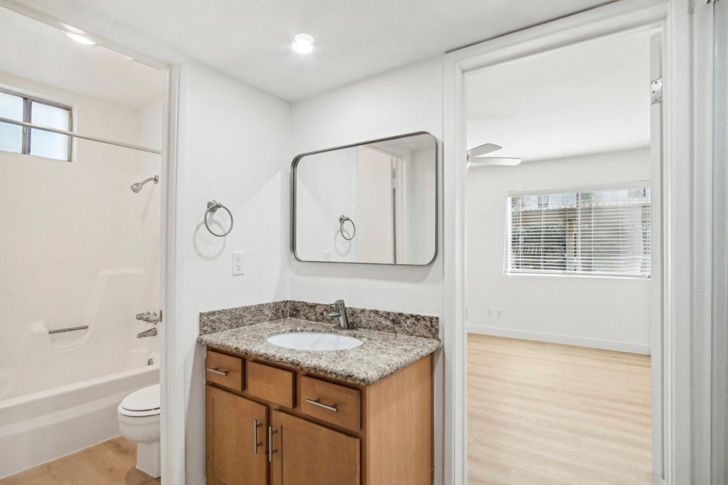A bathroom with a sink, mirror, and toilet. at The Viridian Apartments, Scottsdale, AZ