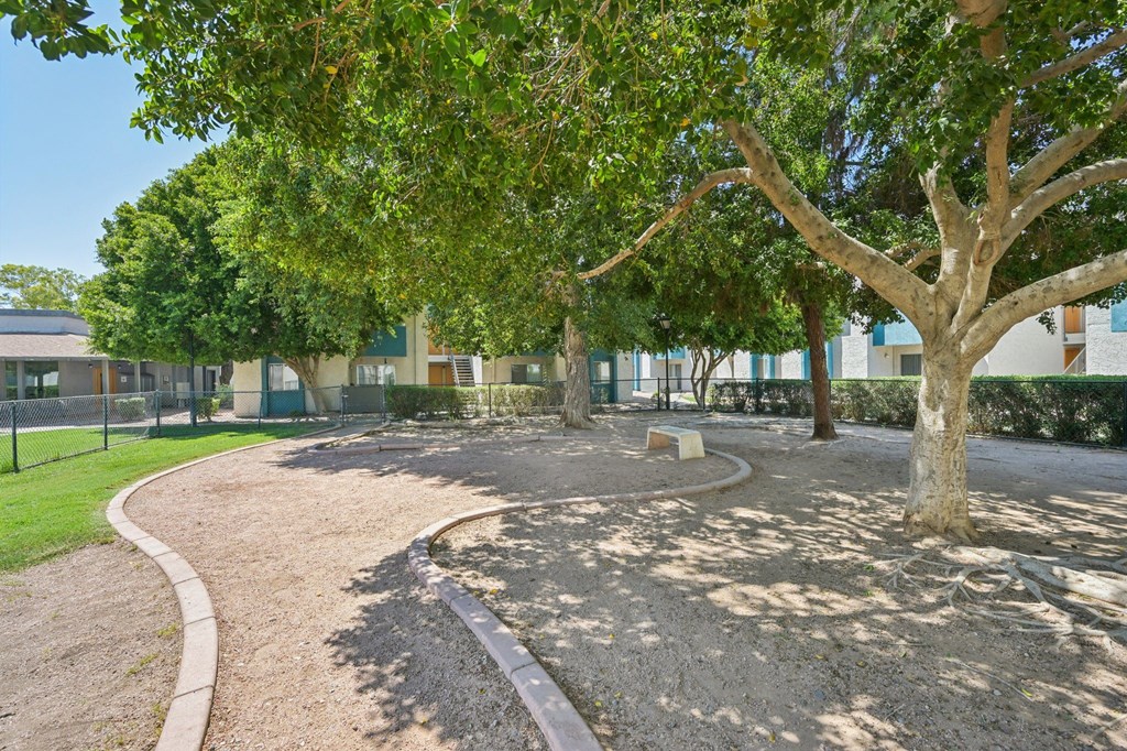 A playground with a curved path and a tree in the foreground.